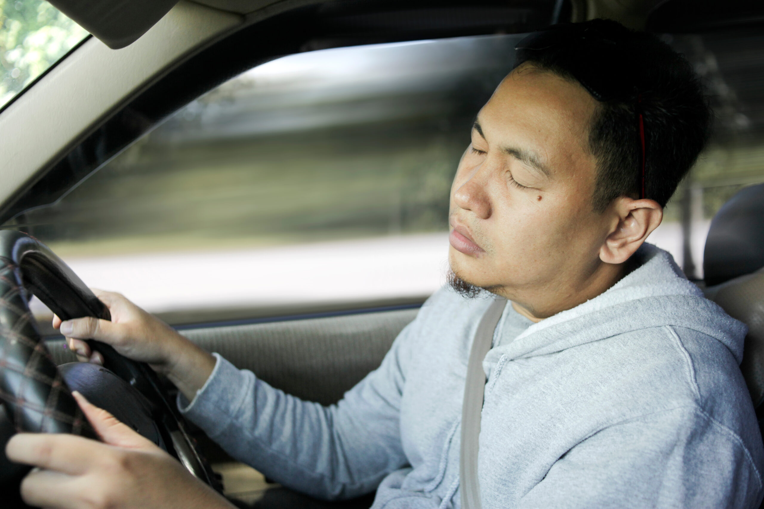 fatigued driving man with eyes closed behind the wheel