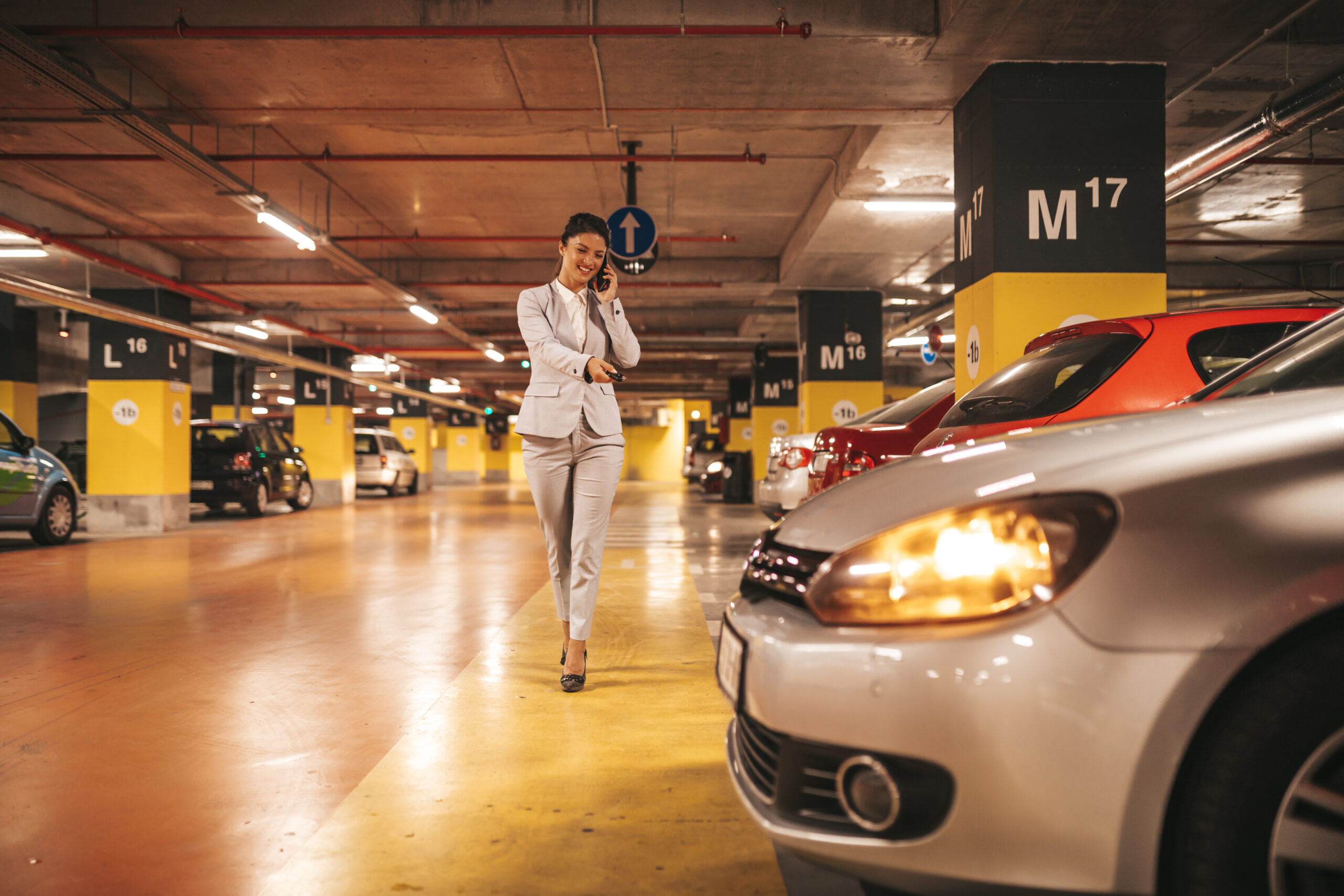 woman on phone walking to car in parking garage