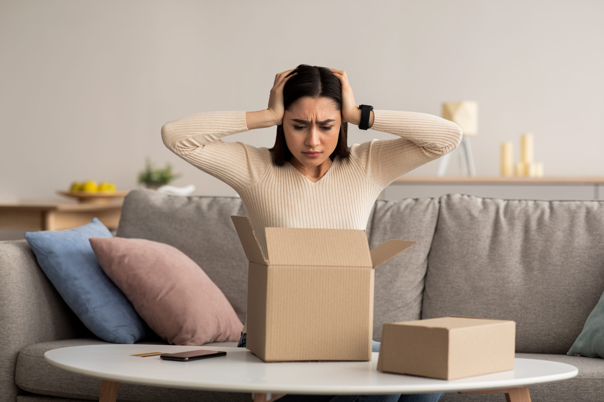 woman with hands on head looking at a box