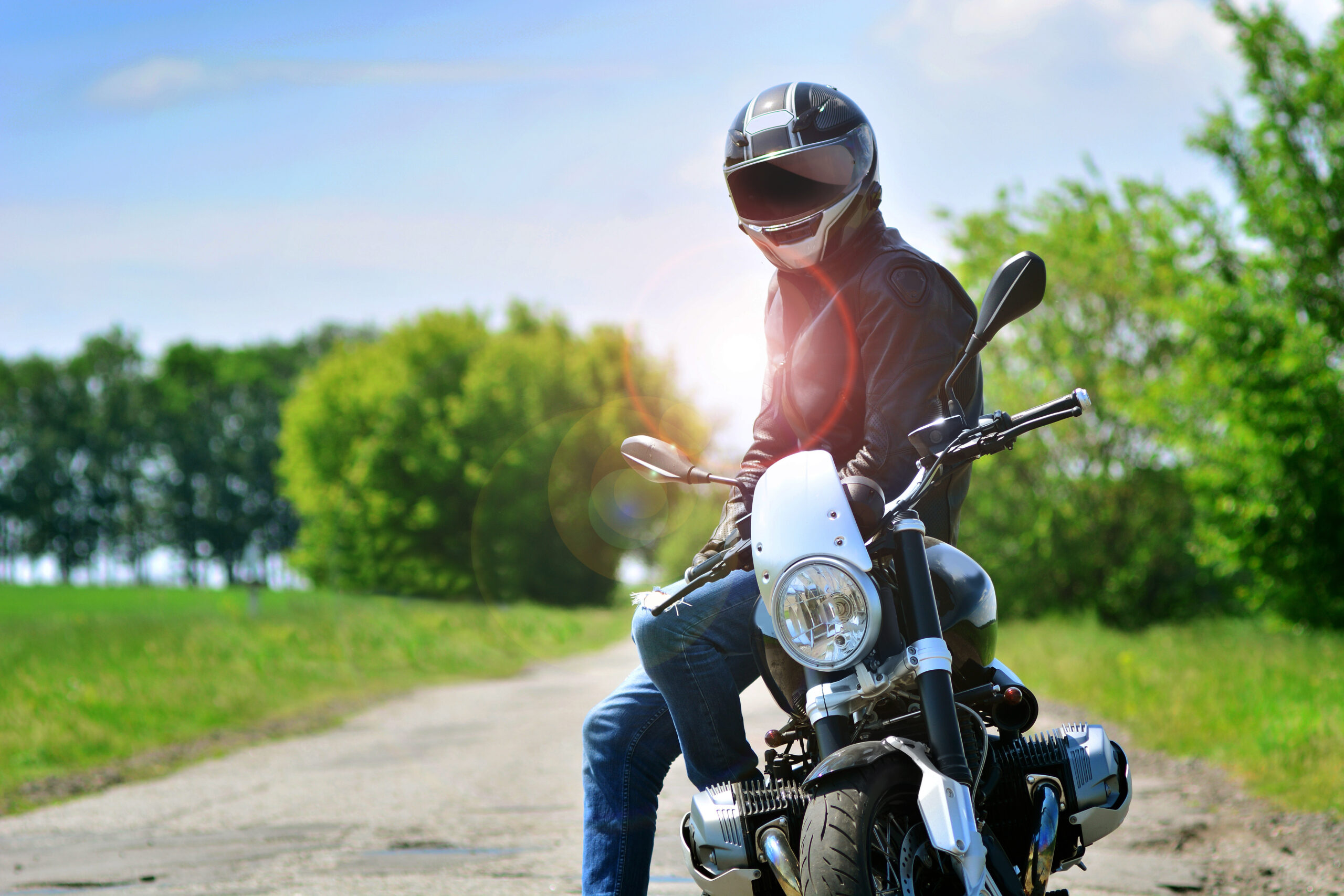 Motorcyclist in helmet and leather jacket sits on his motorcycle outdoors. Motorbike travelling background.