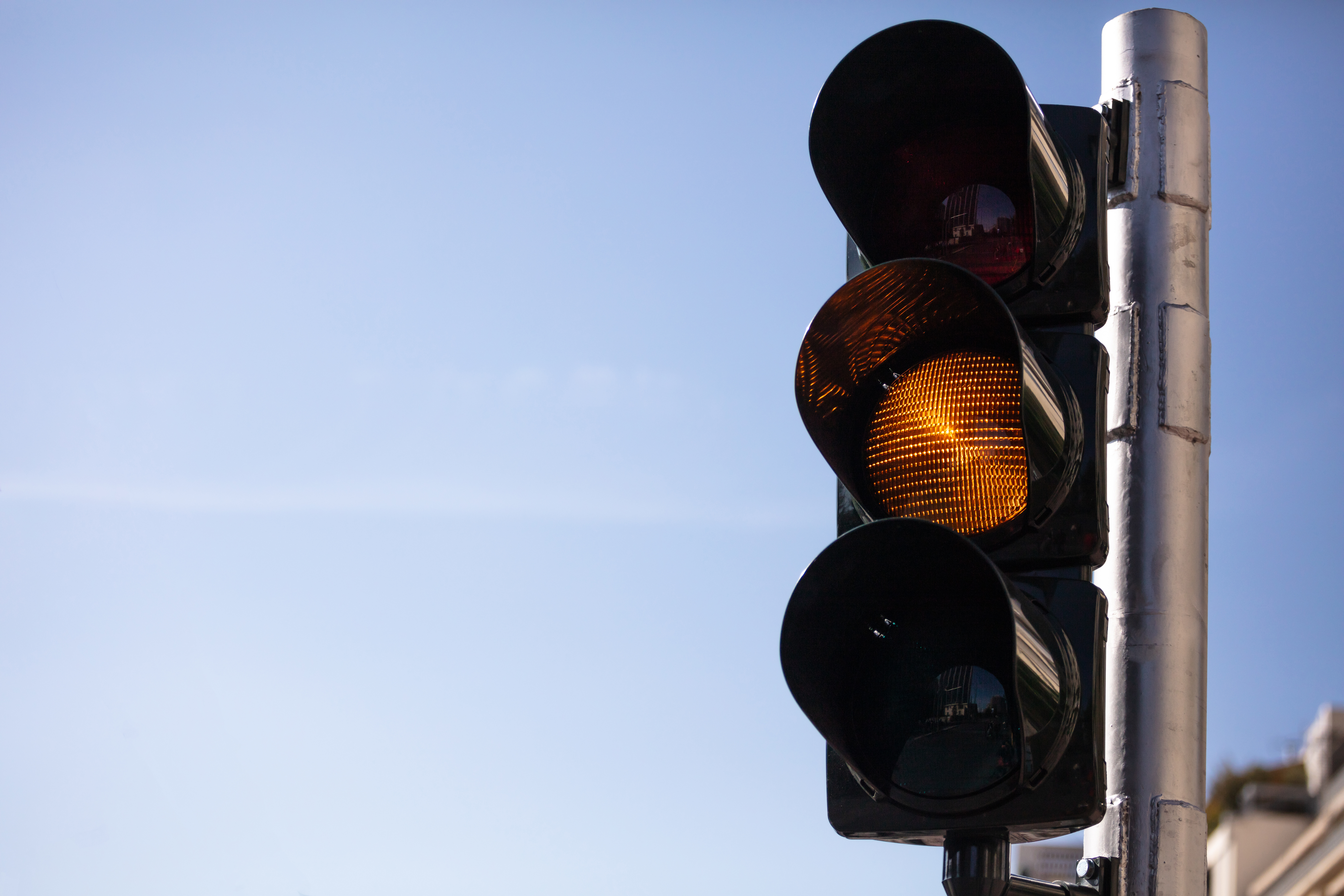 Amber, yellow traffic lights for cars, blue sky background
