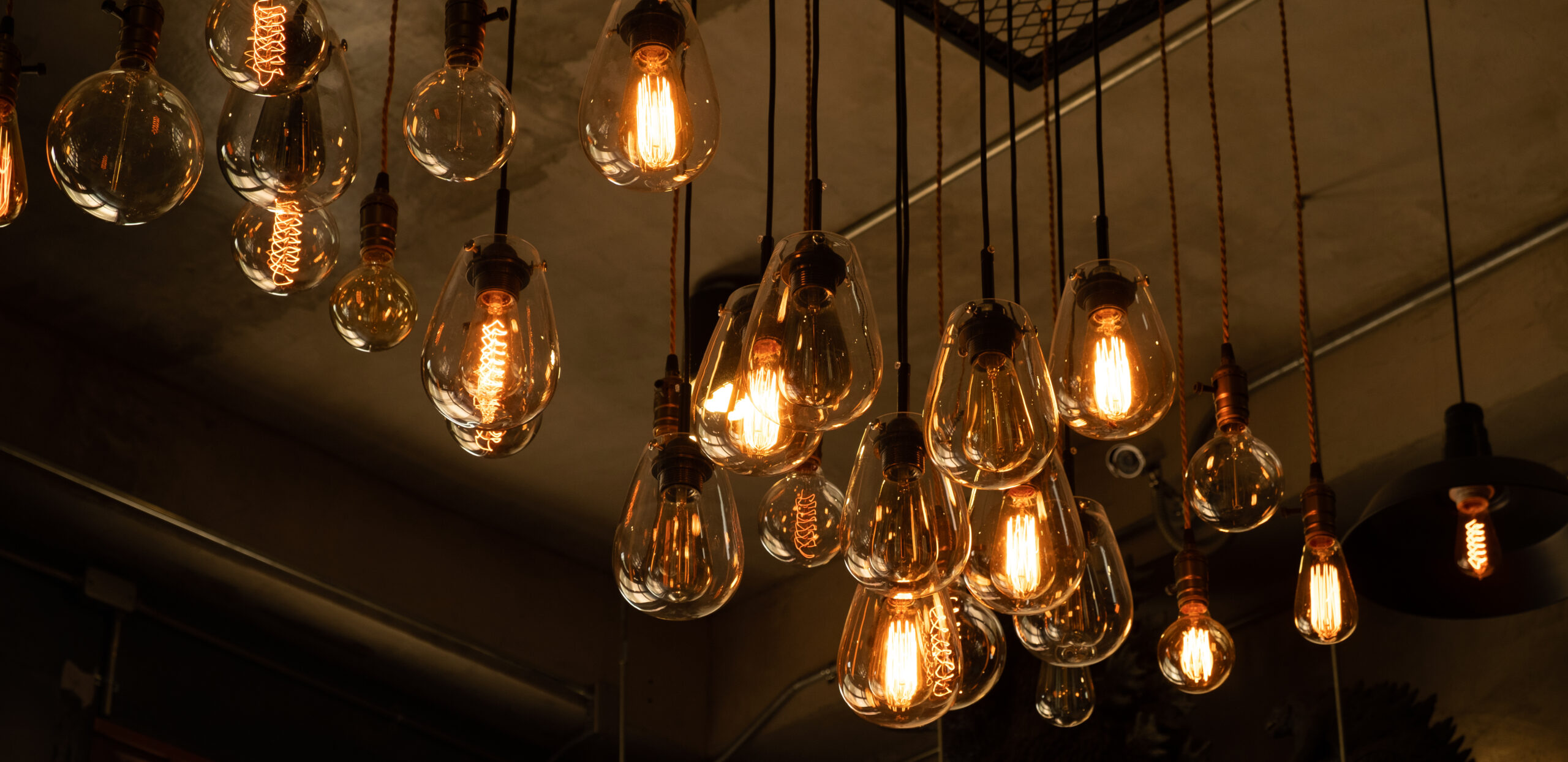 House interior of loft and rustic style. Beautiful vintage luxury light bulb hanging decor glowing in dark. Retro filter effect style. Blend of history and modern.