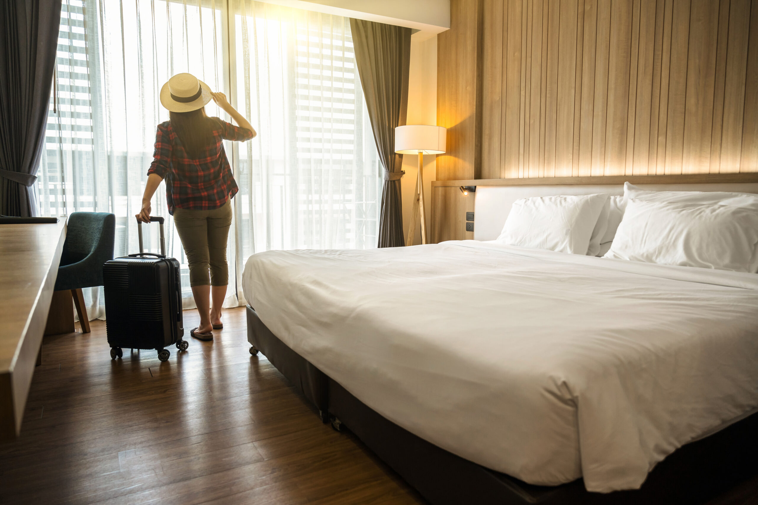 Happiness traveler woman standing with baggage in bedroom of hotel or hostel when traveling on her holiday, luxury interior bedroom design, tourism and travel concept