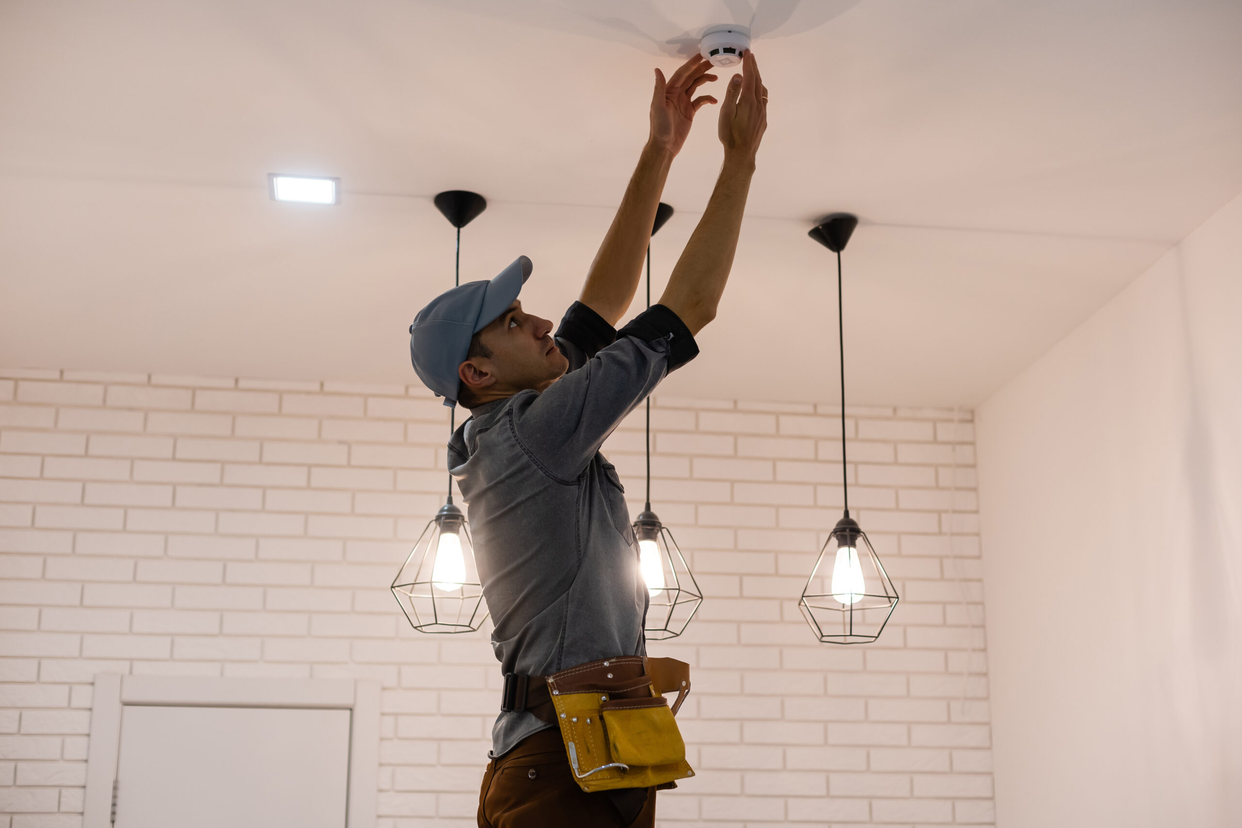 Handyman installing a smoke detector on the ceiling.